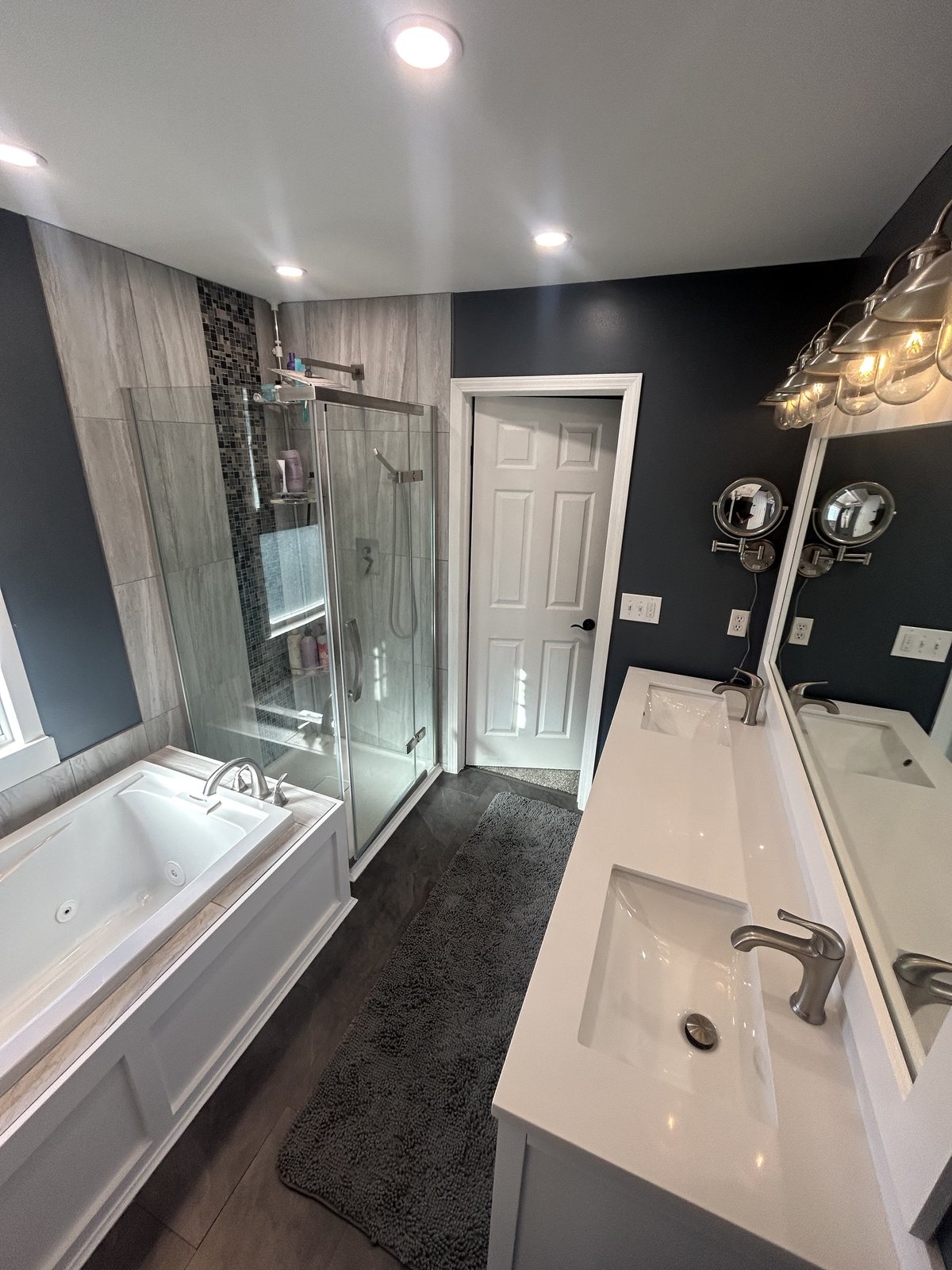 Finished bathroom with a tub, glass shower enclosure, vanity, and dark accent walls