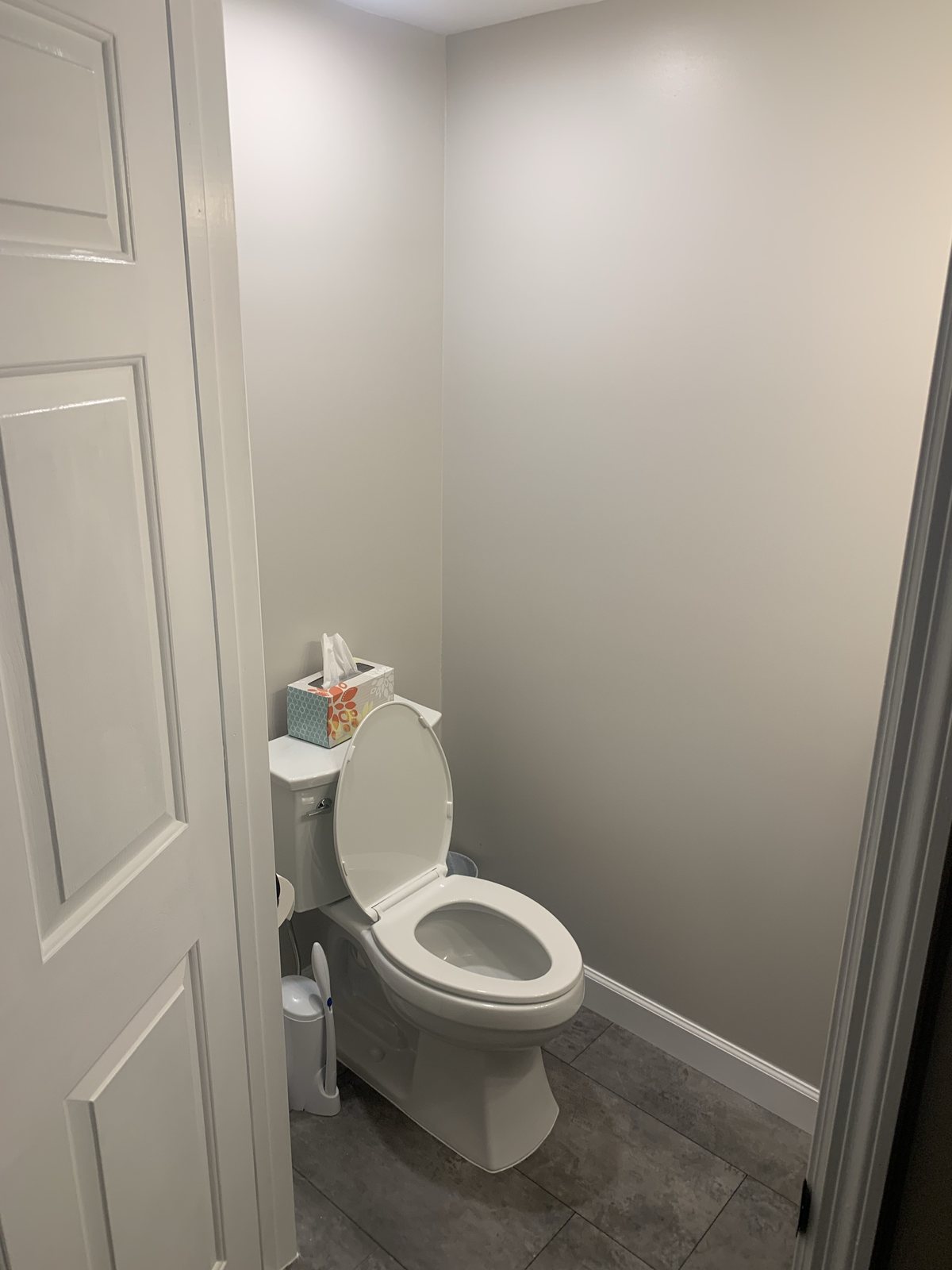 Finished bathroom toilet area with gray walls, white trim, and tile flooring