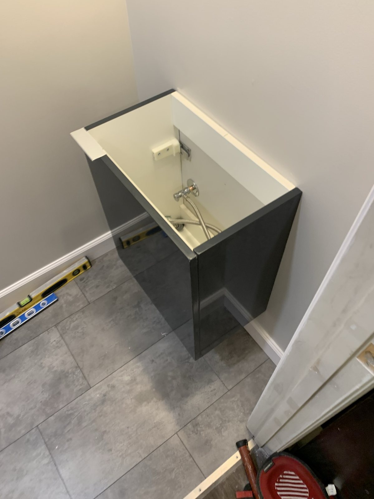 Bathroom vanity installation in progress with the cabinet open and leveling tools nearby