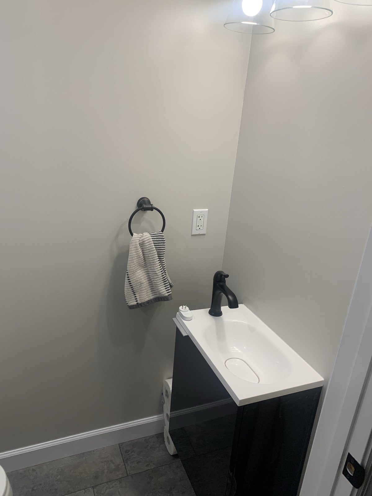Finished bathroom vanity area with black faucet, towel ring, and wall light