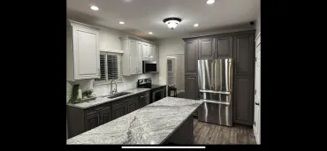 Wide view of a finished kitchen with two-tone cabinetry and a granite island