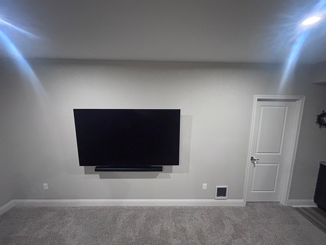 Original light-colored wall and mounted television before the TV feature-wall installation